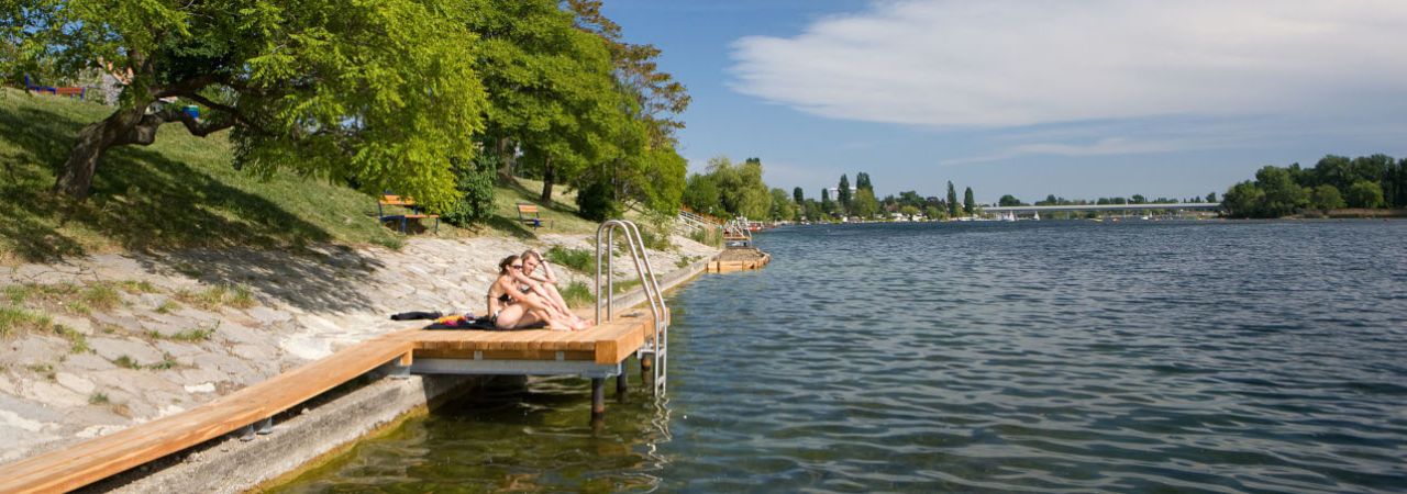 Ein Pärchen sitzt auf einem Badesteg