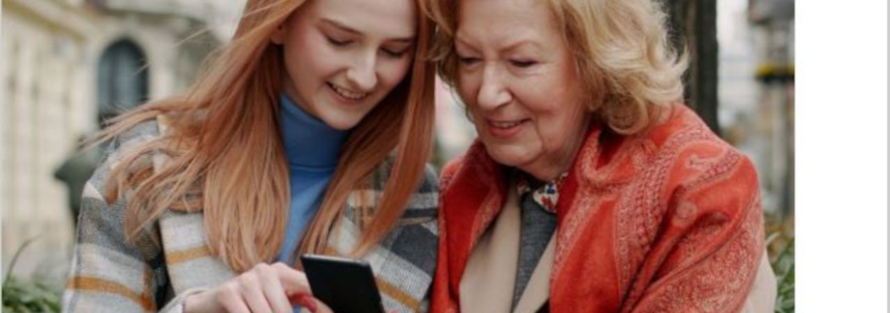 Junge und ältere Frau benutzen gemeinsam ein Smartphone