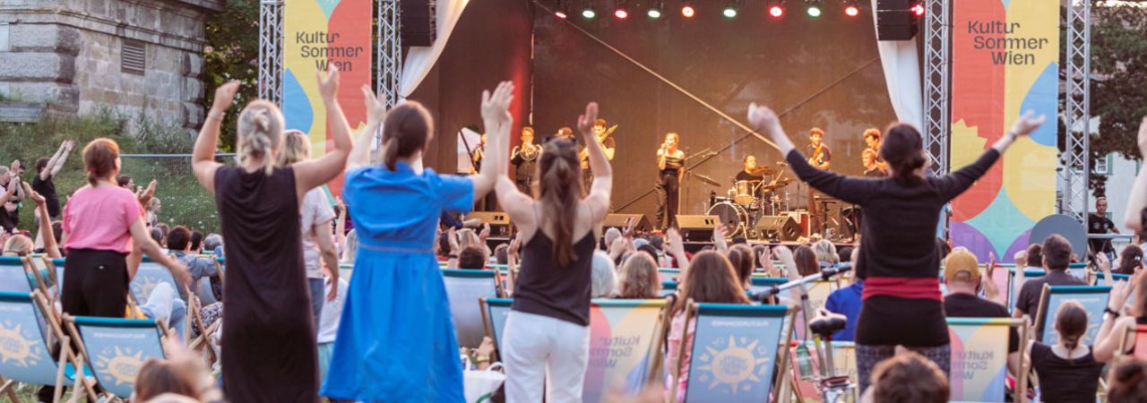 Tanzendes Publikum vor der Bühne bei einem Open Air Konzert im Rahmen des Kultursommers Wien.